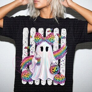 May include: A black t-shirt featuring a graphic of a white ghost wearing a large leopard print bow. The ghost holds a leopard print coffee cup and a jack-o'-lantern bucket, surrounded by rainbow wings, bats, and leopard print pumpkins.