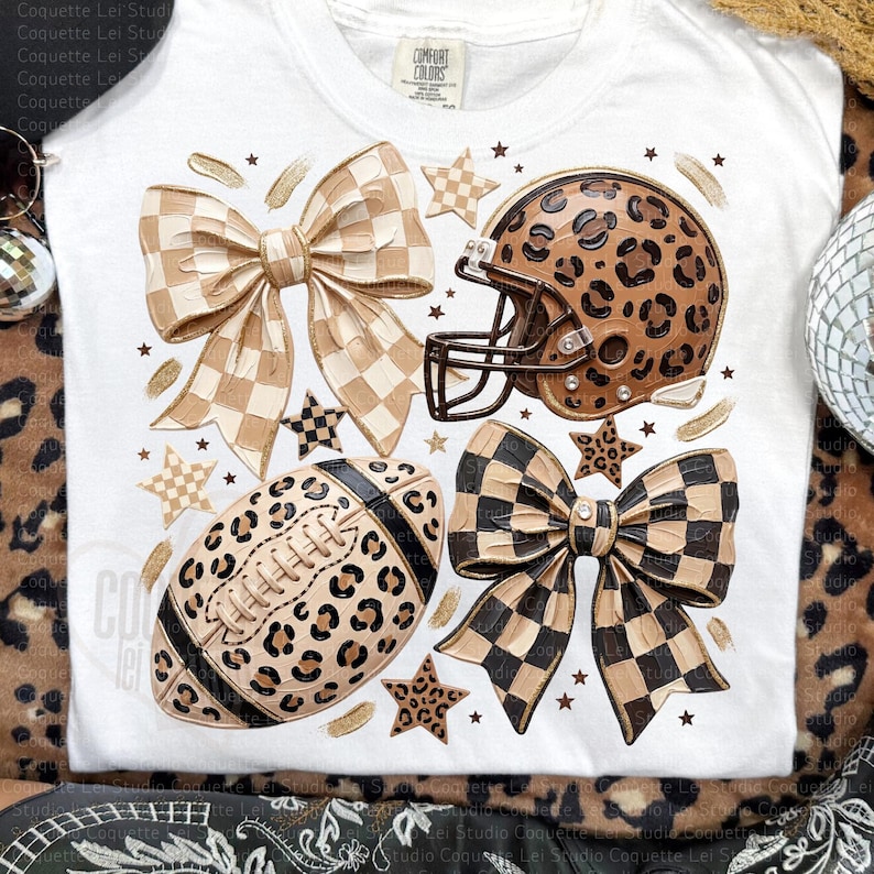 May include: A white t-shirt featuring a graphic print of a football helmet with a leopard print pattern, a football with a leopard print pattern, two large bows with checkered patterns, and several small stars scattered across the design.