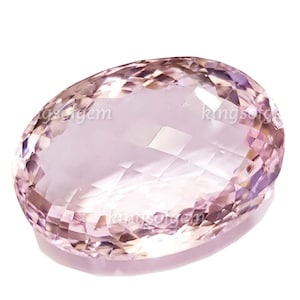 May include: A faceted, oval-shaped gemstone with a pale pink hue. The gem has a high degree of clarity, with multiple facets that reflect light. The image is set against a white background, highlighting the gem's color and shape. The gem is likely a rose quartz or similar gemstone.