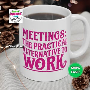 White ceramic mug with the phrase “Meetings: The Practical Alternative To Work” in bold pink text, styled on a black marble countertop in a luxury condo. Perfect gift for co-worker, colleague, boss - friend mum dad girlfriend boyfriend husband wife partner or special person in your life.