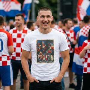 Man in World Cup fan zone wearing white Croatia football tee with faded red white and blue colours, distressed retro football lettering and summer 2026 tournament energy.