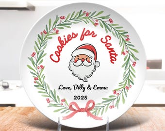 May include: White ceramic plate with a Santa Claus illustration in the center, surrounded by a green and red wreath. The plate reads "Cookies for Santa" and includes the names "Love, Billy & Emma" and the year "2025".