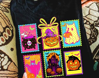May include: Black t-shirt featuring colorful Halloween-themed postage stamp designs. The stamps depict a cauldron, jack-o'-lanterns, ghosts, a haunted house, and a black cat. The designs are outlined in bright neon colors.