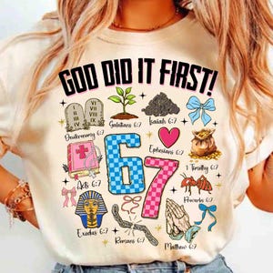 May include: Cream-colored t-shirt with the text "GOD DID IT FIRST!" in black. The shirt features various religious symbols and the numbers "67" in blue and pink checkered patterns. Additional text includes Bible verses.
