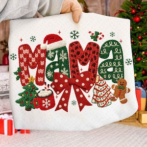 May include: White Christmas-themed fabric with the word "MAMA" in red and green knit-style letters. The design includes a Santa hat, snowflakes, a bow, a Christmas tree, a mug of hot chocolate, a gingerbread man, and candy canes.