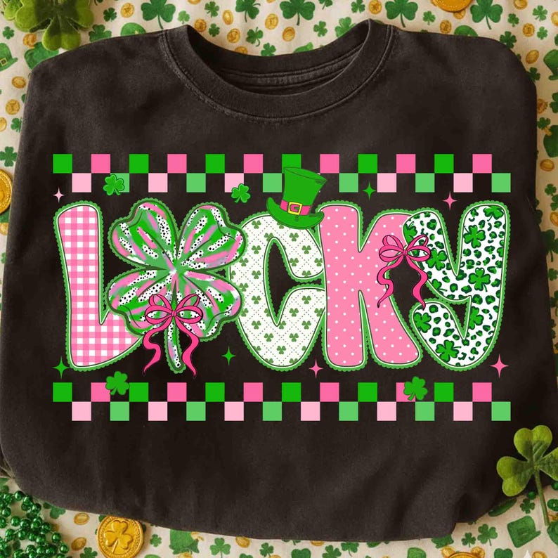 May include: Black sweatshirt with the word "LUCKY" in pink, green, and white, with a four-leaf clover and a leprechaun hat. The letters have various patterns, including gingham and polka dots. The design is framed with a green and pink checkered border.