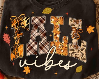 May include: Black sweatshirt with the words "FALL VIBES" in a decorative font. The letters are filled with various patterns, including leopard print, plaid, and floral designs. Autumn leaves and stars surround the text.