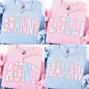 Pode incluir: Quatro camisolas em azul claro e rosa, cada uma com um nome diferente em padrões florais e xadrez: "Granny", "Lolli", "Aunt" e "Mamaw". Cada camisola tem um colar de prata. As camisolas estão planas.
