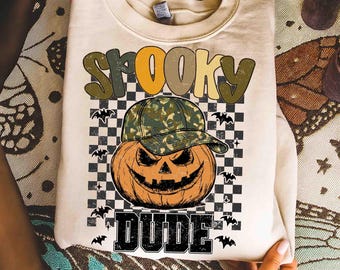Può includere: Felpa color crema con grafica a tema Halloween. Il design presenta una zucca con un berretto da baseball mimetico, la parola "SPOOKY" sopra e "DUDE" sotto, il tutto su uno sfondo a scacchi in bianco e nero con sagome di pipistrelli.