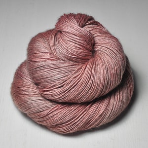 Könnte beinhalten: Ein Knäuel weicher, rosafarbener Wolle mit einem subtilen Schimmer. Die Wolle besteht aus einer Mischung aus Seide und Wolle und ist perfekt zum Stricken oder Häkeln.