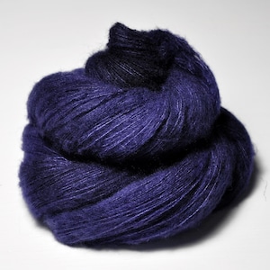 May include: A skein of deep purple yarn, with a slightly darker shade of purple in the centre, is twisted into a loose ball shape.