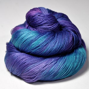 Peut inclure: Une pelote de fil de couleur violet, bleu sarcelle et bleu. Le fil est teint à la main et présente un motif de couleur varié.