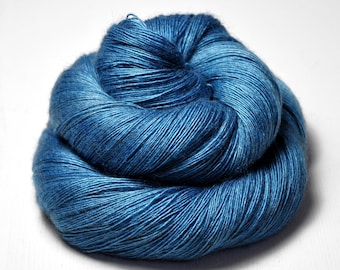 May include: A skein of deep blue yarn, made of a soft, natural fiber. The yarn is tightly wound and has a subtle sheen.