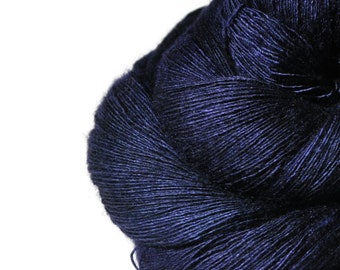 May include: A close-up of a ball of dark blue yarn. The yarn is tightly wound, with visible strands and a slight sheen. The color is a deep, rich shade of blue, suitable for knitting or crocheting projects.