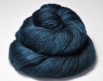 May include: A skein of dark teal yarn, tightly wound into a round shape. The yarn has a slight sheen, reflecting light and creating subtle variations in color. The texture of the yarn is visible, with individual strands appearing to be tightly twisted together.