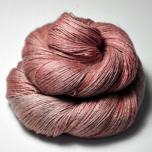 Könnte beinhalten: Ein Knäuel weiches, rosafarbenes Garn mit einem subtilen Schimmer. Das Garn besteht aus einer Mischung aus Seide und Leinen und ist perfekt zum Stricken oder Häkeln von zarten Kleidungsstücken.