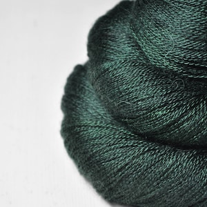 Könnte beinhalten: Eine Nahaufnahme eines tiefgrünen Garnknäuels. Das Garn ist weich und flauschig und perfekt zum Stricken oder Häkeln.