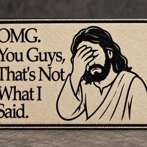 May include: A rectangular beige sign with a black border featuring a black line art illustration of a bearded figure with long hair performing a facepalm gesture. The text reads: OMG. You Guys, That's Not What I Said. The surface has a textured finish.
