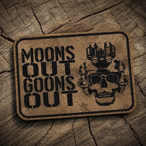 May include: A rectangular tan patch with a black border featuring the engraved text MOONS OUT GOONS OUT and a graphic of a human skull wearing a tactical helmet equipped with night vision goggles, rendered in a dark, high-contrast style.