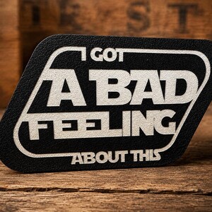 May include: A black rectangular patch with rounded corners featuring white embossed text that reads I GOT A BAD FEELING ABOUT THIS. The design is enclosed within a white border line that follows the shape of the patch, creating a bold graphic.