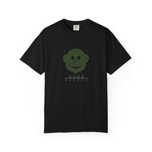 May include: Black t-shirt with a green monkey face design made of code. The word "code" is above the monkey face, and the word "monkey" is below it. The shirt is a short-sleeved crew neck.