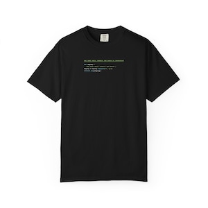 May include: Black t-shirt featuring green and blue text: "THE USER SHALL INHERIT THE EARTH IN JAVASCRIPT" and lines of code. The shirt has a crew neck and short sleeves.