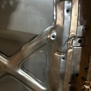 Peut inclure: Vue intérieure d'un capot de voiture argenté. Le dessous du capot présente des supports structurels, des découpes et des trous de montage. La surface métallique reflète la lumière, soulignant les contours et les détails.