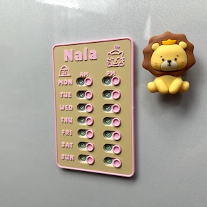 May include: A magnetic weekly planner with the name "Nala" in pink lettering, featuring a cat icon and a lion-shaped magnet. The planner has AM/PM toggles for each day of the week, with a pink border.