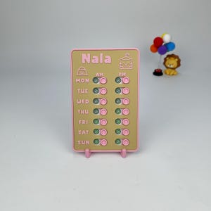 May include: A pink and tan pet care schedule with the name "Nala" at the top. The schedule has checkboxes for each day of the week, with AM and PM options. A small lion figurine and a balloon cluster are in the background.
