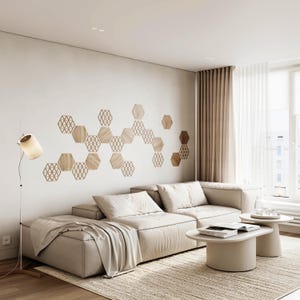 Puede incluir: Salón moderno con un sofá seccional beige, dos mesas de centro redondas y una alfombra estampada. La pared presenta una disposición decorativa de paneles hexagonales de madera. Una lámpara de pie con pantalla cilíndrica proporciona luz suave.