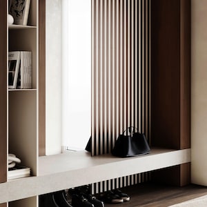 May include: A modern entryway with a built-in bench and shelving. A black leather handbag sits on the bench. The background features vertical brown and white striped paneling and a dark wood floor. Several pairs of black shoes are visible below the bench.