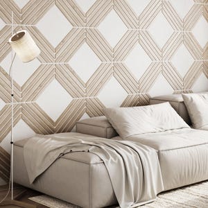 May include: A modern living room featuring a beige sectional sofa with white pillows and a matching throw blanket. A floor lamp with a beige lampshade stands beside the sofa. The wall has a geometric pattern in white and light brown.