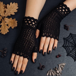 May include: A pair of black fingerless gloves featuring a delicate crochet pattern with a scalloped edge at the wrist and knuckles. The gloves are crafted from a fine black yarn, showcasing an intricate openwork design that covers the hand.