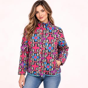 May include: A long-sleeve jacket featuring a vibrant geometric pattern in shades of hot pink, bright blue, black, and white. The jacket has a high collar, a front zipper closure, and a straight hemline, paired with blue denim jeans.
