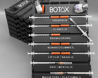 May include: Black plastic organizer with the word "BOTOX" in white. The organizer holds syringes and vials, labeled for various facial areas like Frontalis, Glabella, and Brows/Crows. The syringes have orange plungers.