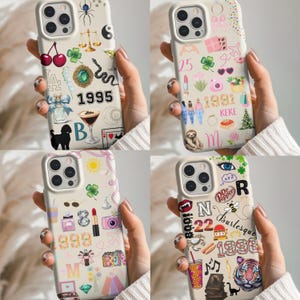 May include: Four phone cases with various designs. One case features cherries, the number 1995, and a black dog. Another has the number 25, a sloth, and the word "KEKE". The third case has the number 999 and a lipstick. The last case has the number 22 and the word "Burlesque".
