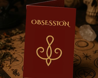 May include: A maroon card with the word "OBSESSION" in gold script at the top. Below the text is a gold, stylized symbol. The card is open, revealing a blank interior. The background includes a skull and other occult items.