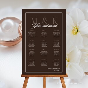 Puede incluir: Un cartel de plano de asientos de boda marrón oscuro con texto blanco que dice M & K Your seat await, listando invitados para las mesas 1 a 12, y mostrando los nombres Michelle & Kelvin con la fecha 07.05.20XX al pie, sobre un caballete de madera.