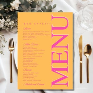 Op de afbeelding: Een rechthoekige menukaart met een feloranje achtergrond en opvallende roze tekst. Het woord MENU staat verticaal in grote letters aan de rechterkant gedrukt. De tekst bevat secties voor Starter, Main Course, Chef's Selection en Desserts.
