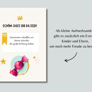 Pu&ograve; includere: Un biglietto di auguri con testo in tedesco, una corona d'oro, uno striscione giallo con un cuore e una caramella rosa. La carta include le frasi "SCH&Ouml;N. DASS IHR DA SEID!" e "Gemeinsam schaffen wir kleine Schritte, die gro&szlig;e Wirkung haben."