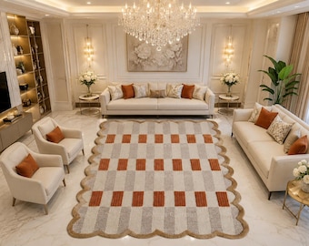 May include: A rectangular area rug featuring a repeating geometric pattern of alternating light gray and burnt orange vertical rectangular blocks, finished with a scalloped edge border in a solid tan color, placed in a living room setting.