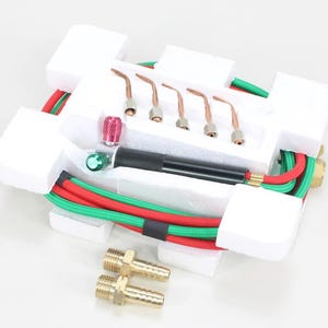 May include: A new oxy-acetylene torch kit, featuring a black handle, copper tips, and red and green hoses. The kit includes brass fittings and is packaged in a white foam insert.