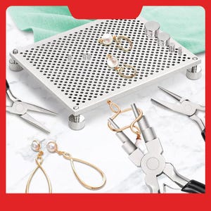 May include: A jewelry-making station with a perforated metal work surface, various tools, and finished earrings. The earrings feature gold-colored metal and white pearls. Pliers and other components are also visible, suggesting a crafting theme.