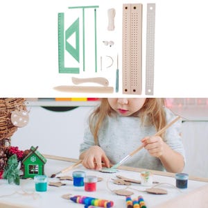 May include: A craft kit with various tools, including rulers, a triangle, a wooden board with holes, and a curved wooden tool. The kit also includes a needle, thread, and a small pair of glasses. A child is painting with brushes and paint.