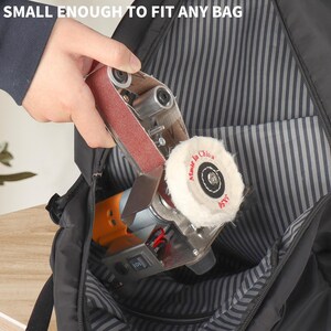 A hand is holding a small sanding machine with a white pad, which is being used to smooth a surface.