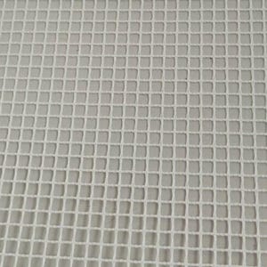 May include: Close-up of a white rug hooking canvas with a grid pattern. The canvas is made of a woven material and is a light cream color. The grid is made of evenly spaced squares.