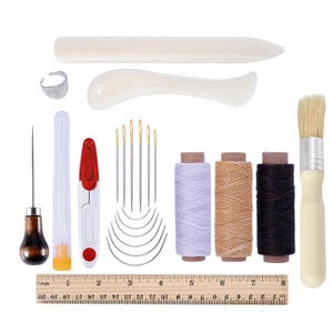 May include: A leathercraft tool kit with various tools, including needles, thread spools, a ruler, a brush, and a thimble. The kit includes a wooden burnisher, a bone folder, and a needle threader. The ruler measures up to 8 inches.