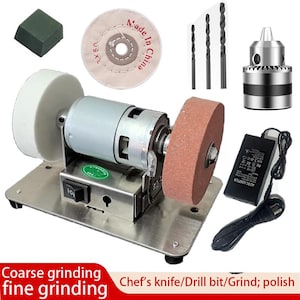 May include: A bench grinder with a silver base, a motor, and two grinding wheels. Additional items include drill bits, a chuck, a polishing wheel, and a power adapter. The text on the image says "Coarse grinding fine grinding" and "Chef's knife/Drill bit/Grind; polish."