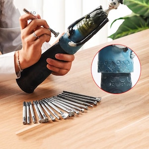May include: A black bottle holder with a decorative figurine and a set of metal tools. The figurine is wearing a blue outfit and a black hat. The tools have various shaped tips.
