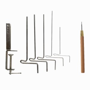 May include: A collection of metal tools for crafting, including a clamp, several wire forms with bent ends, and a wooden-handled awl. The tools are arranged against a white background, suggesting a focus on functionality and precision.